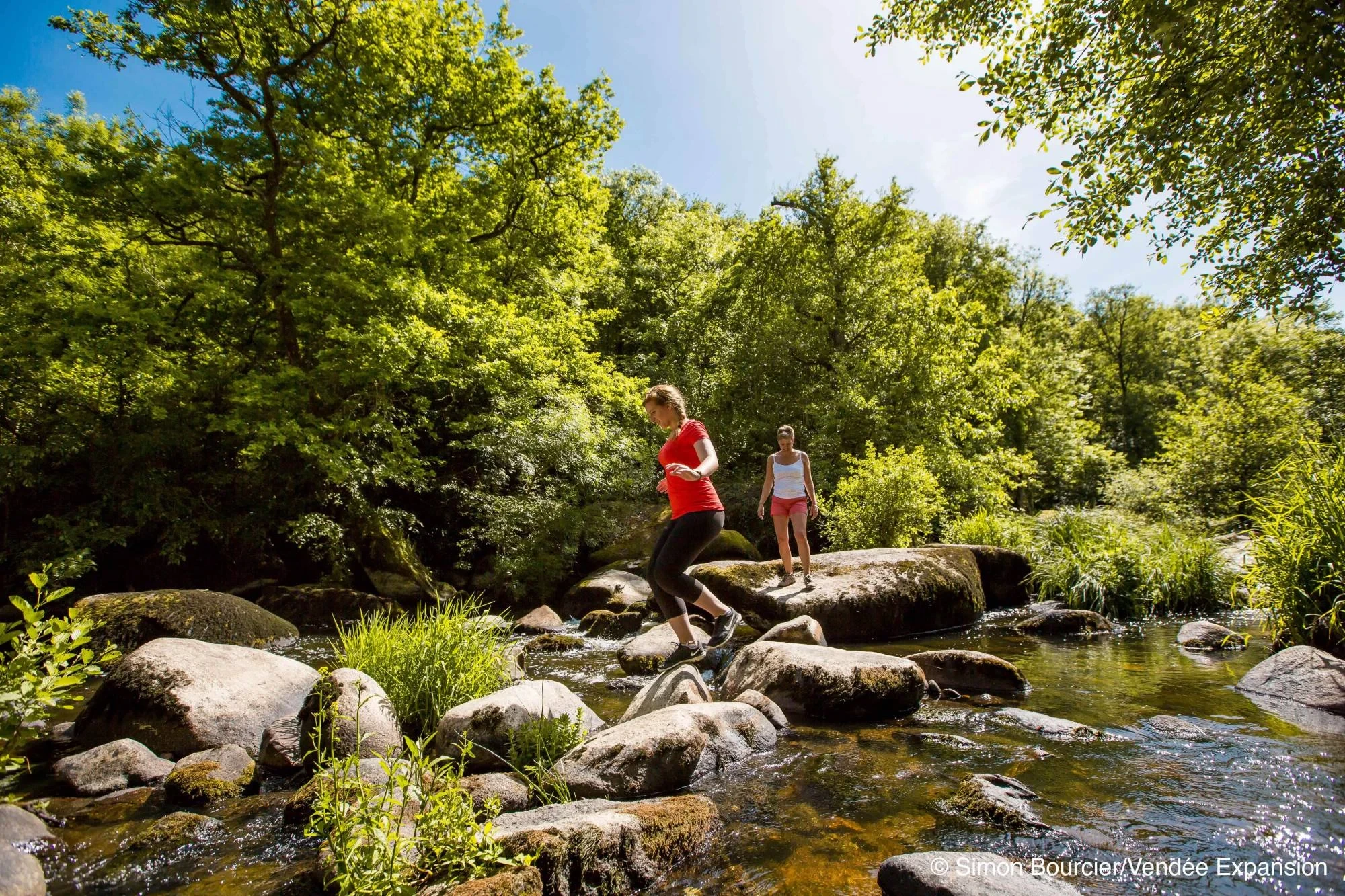 Deux femmes traversant une rivière sur des rochers