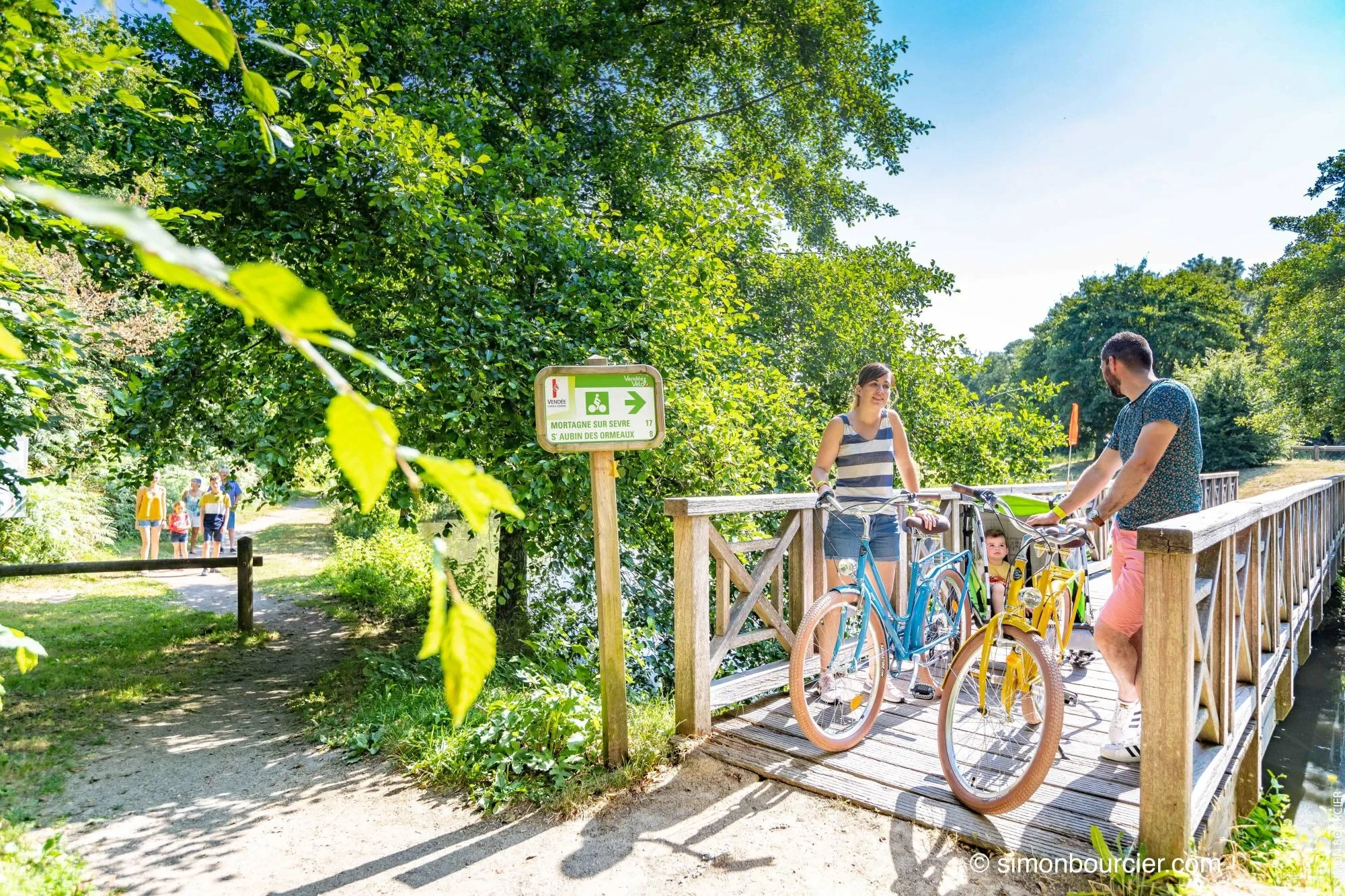 Couple à vélo sur pont en bois verdoyant